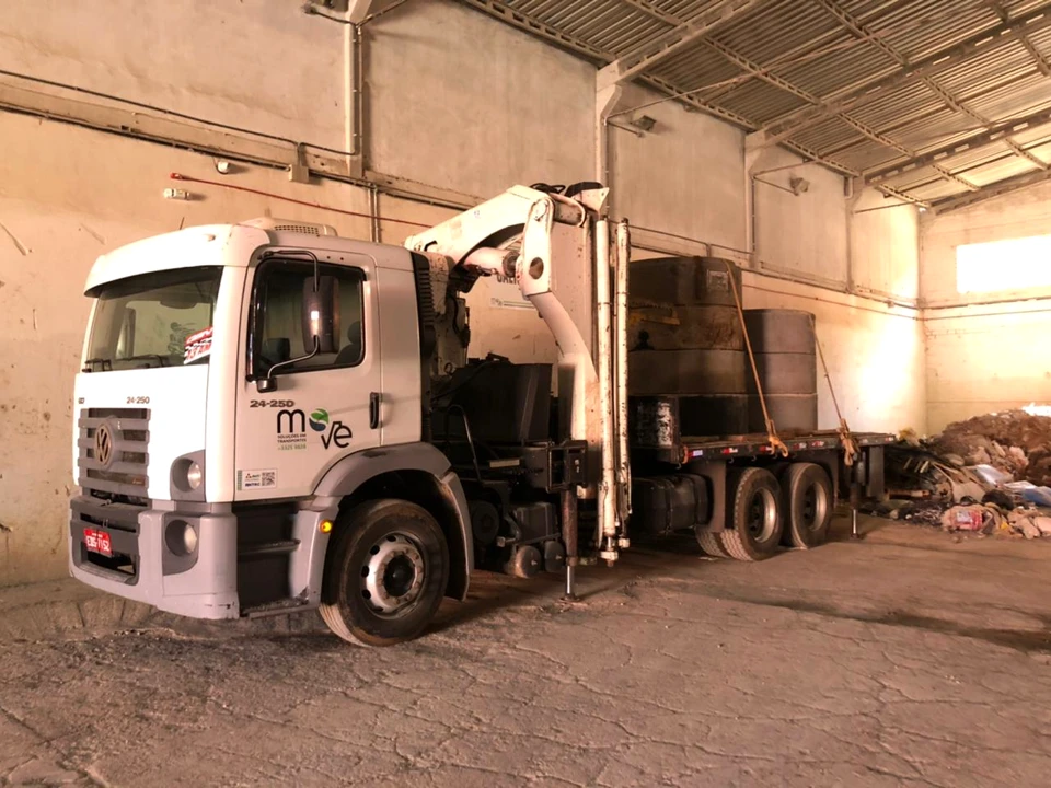 Caminhão branco da Move com guindaste articulado dentro de um galpão.