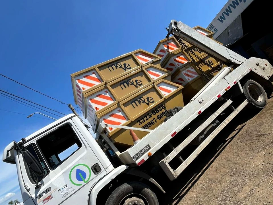 Caminhão branco da Move transportando caçambas amarelas empilhadas, fotografado em ângulo diagonal.